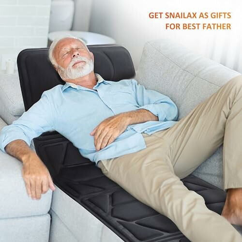 Elderly man relaxing on a massage cushion on a sofa.